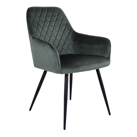 Set van twee House Nordic Harbo eetkamerstoelen in fris groen fluweel met zwarte stalen poten, staand rond een moderne eettafel.