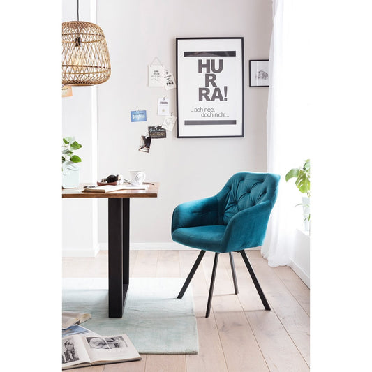 SalesFever eetkamerstoel turquoise fluweel met 360 graden draaifunctie, zwart metalen poten en knoopstiksel, gezien vanuit een moderne setting.