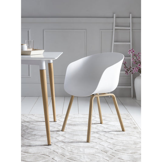 Set van 2 witte SalesFever eetkamerstoelen in Scandinavische schelpstijl met houtlook metalen poten, staand aan een eettafel.